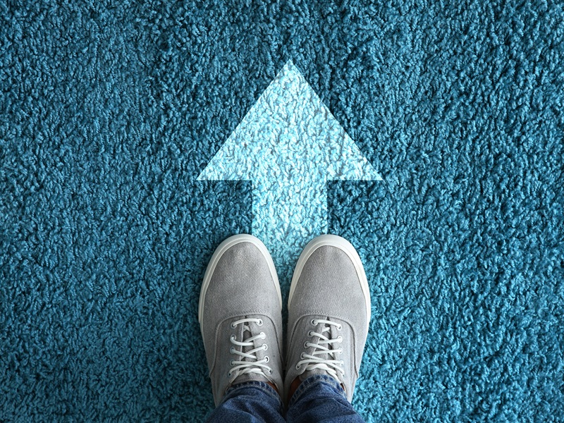 Man standing on carpet with arrow pointing in one direction. Con Man standing on carpet with arrow pointing in one direction. Concept of choice